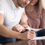 Closeup of young happy couple signing papers, property purchase,