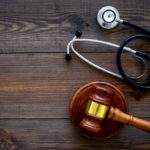 Medical law, health law concept. Gavel and stethoscope on dark wooden backgound top view copy space