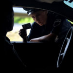 Police woman checking documents of driver, inspection on road, traffic offence