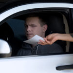 Police woman giving fine receipt to driver on road, traffic offence, inspection