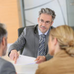 Mature couple signing contract in lawyer’s office