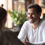 Rear view female sitting at speed dating with smiling man