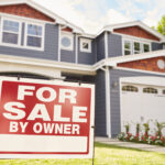 Large suburban house with ‘for sale’ sign displayed outside