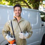 Smiling worker with pesticide sprayer