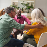 Caucasian senior man consoling crying female during group therap